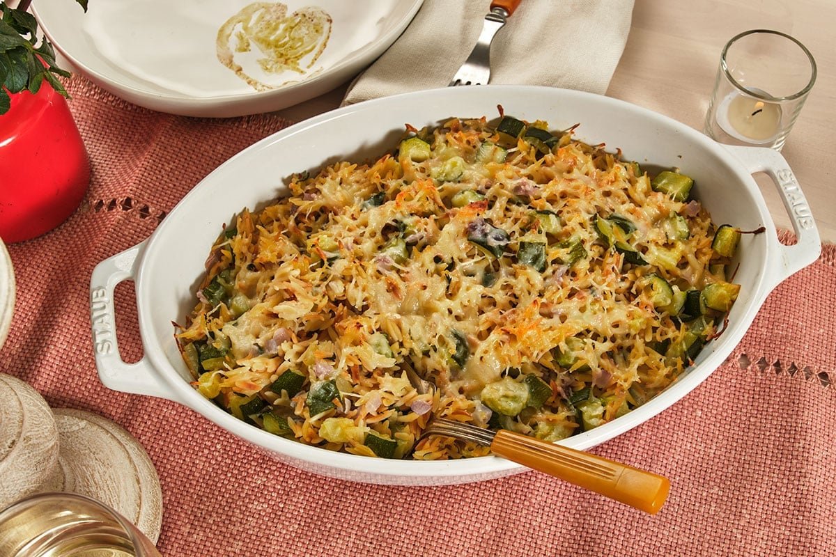 Zucchini casserole with orzo in baking dish on table.